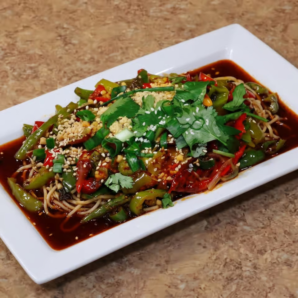 Noodles with green and red peppers, cilantro, sesame seeds, and peanuts in a dark sauce.